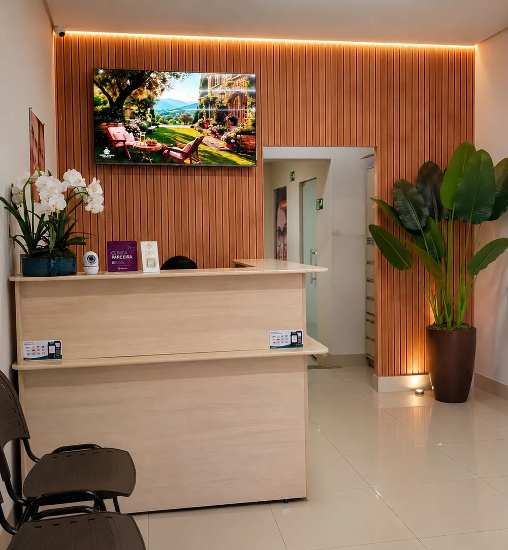 Recepção do consultório com balcão de madeira, painel ripado iluminado e plantas