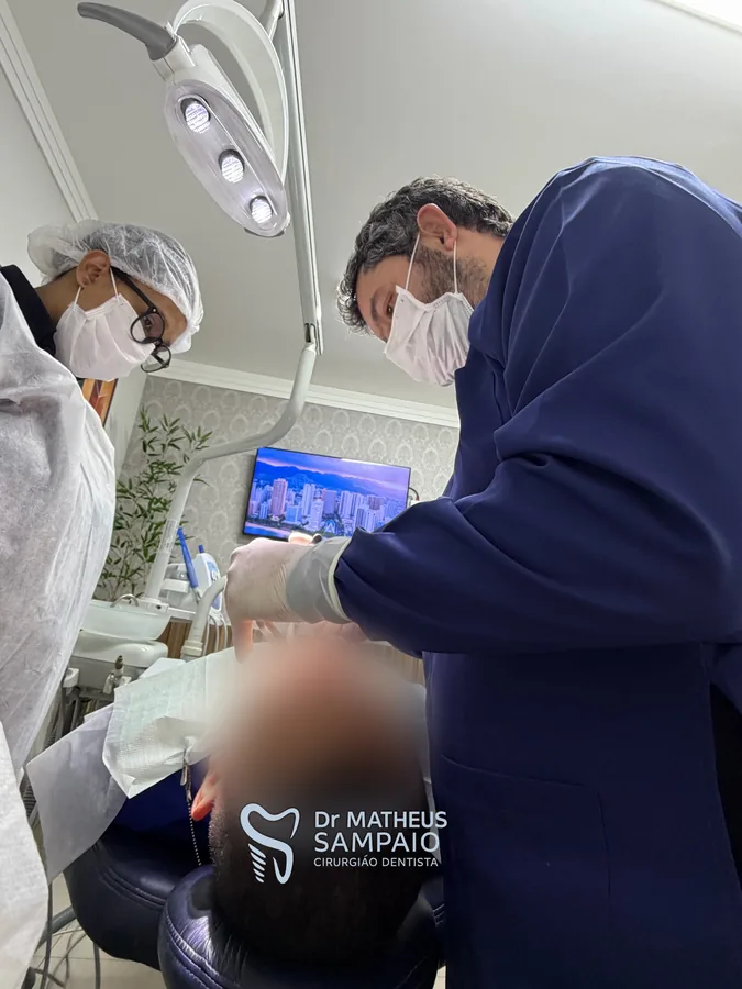 Dr. Matheus, de jaleco azul, e assistente durante atendimento